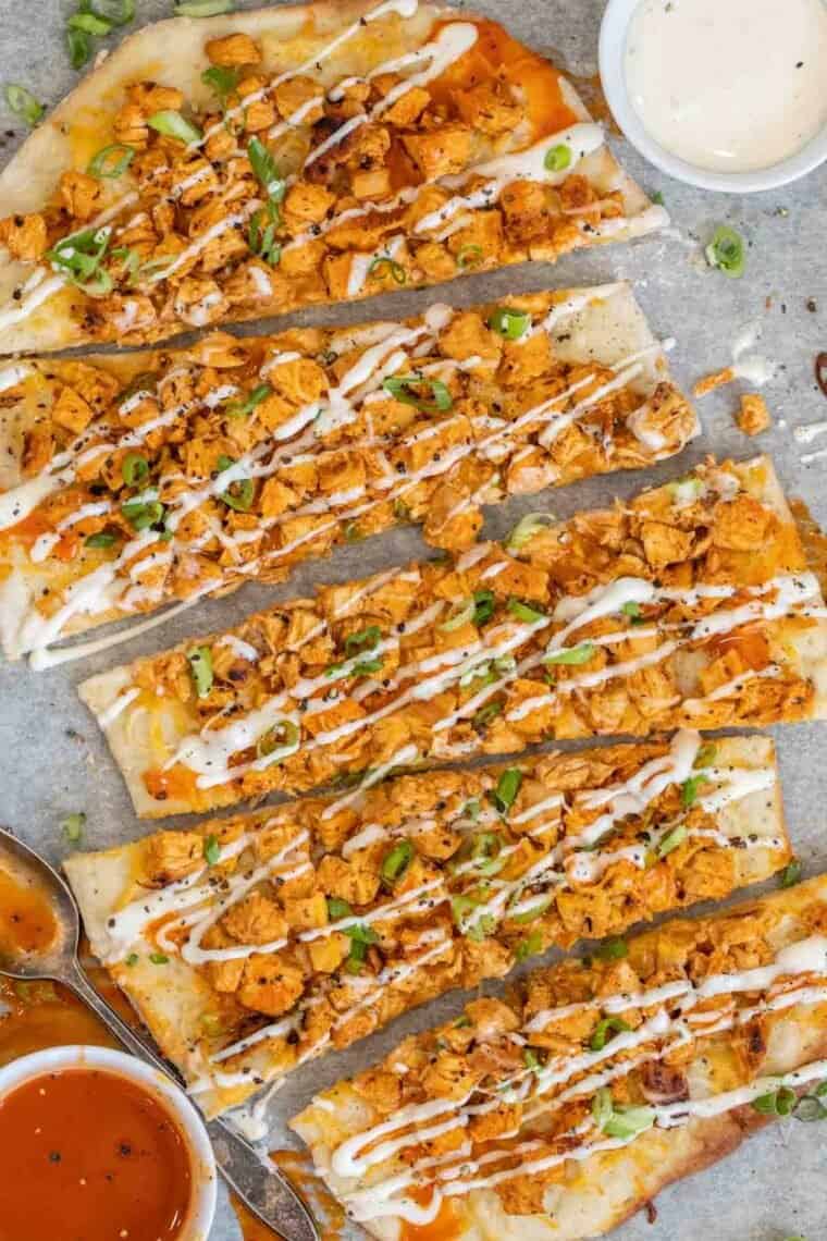Buffalo chicken flatbread sliced and drizzled with green onion. 