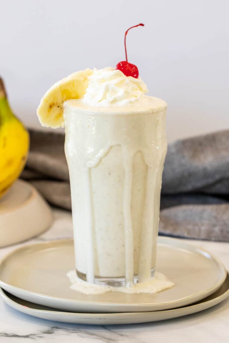 Banana Milkshake recipe served on a plate with a cherry on top.