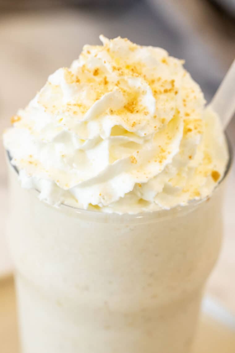 Banana shake in a glass with whipped cream on top.