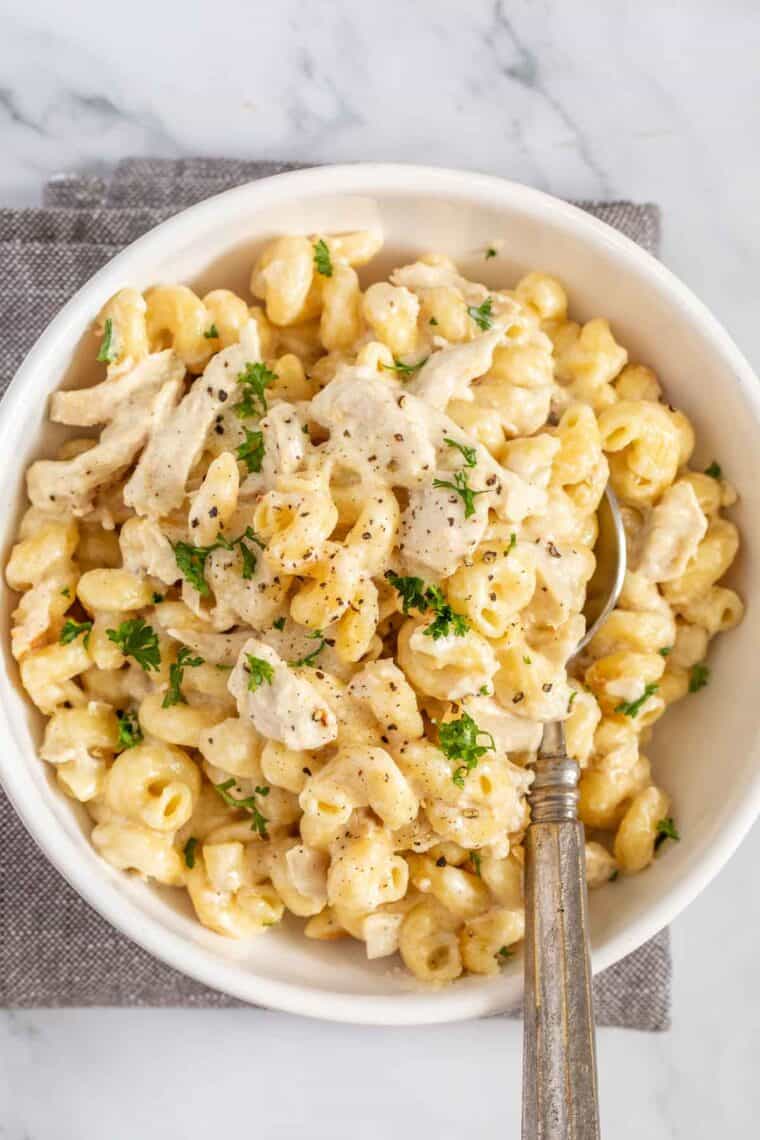 Creamy instant pot alfredo in a white bowl with a spoon. 