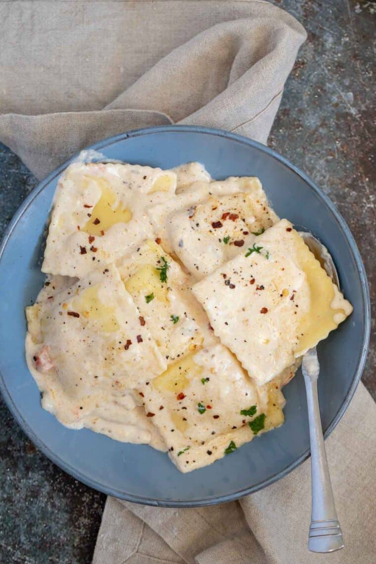 Cheese ravioli in a serving plate with spoon.
