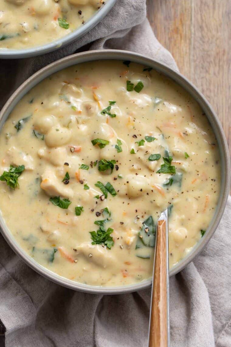 Close up of chicken and gnocchi soup in a bowl with greens.