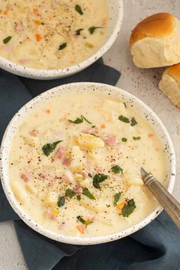 Close up of finished ham and potato soup in serving bowls topped with greens.