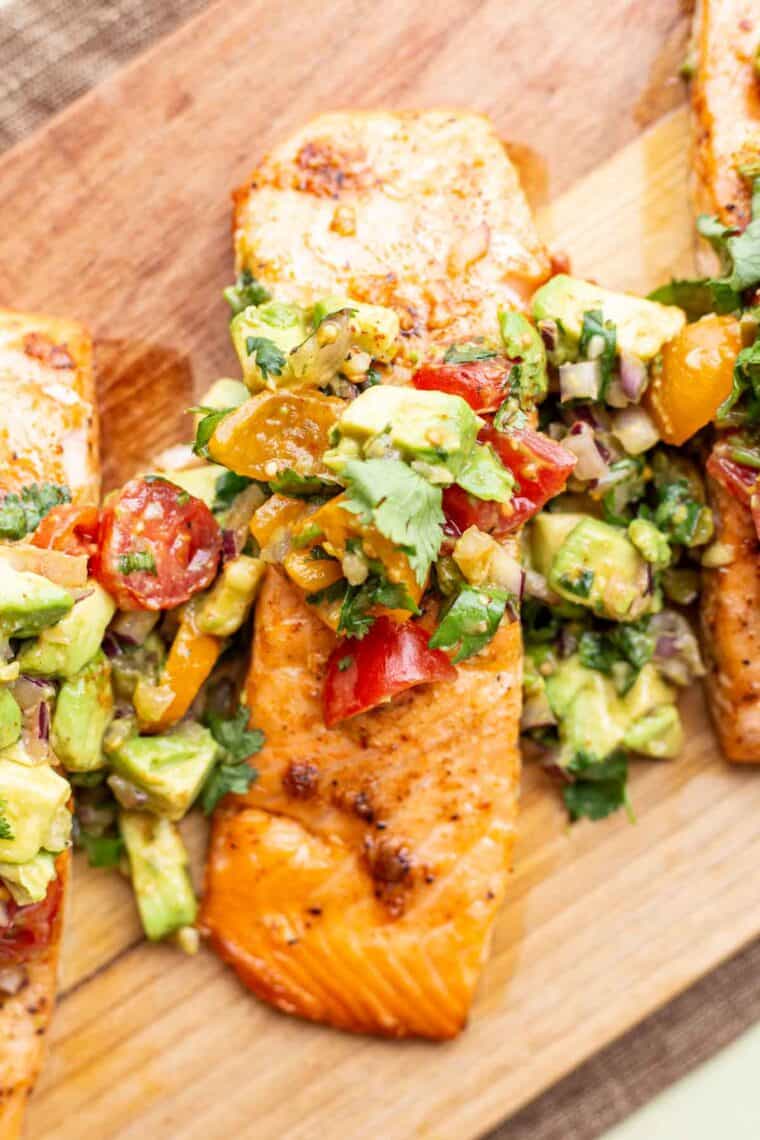 Juicy salmon on a platter topped with avocado guac mixture.