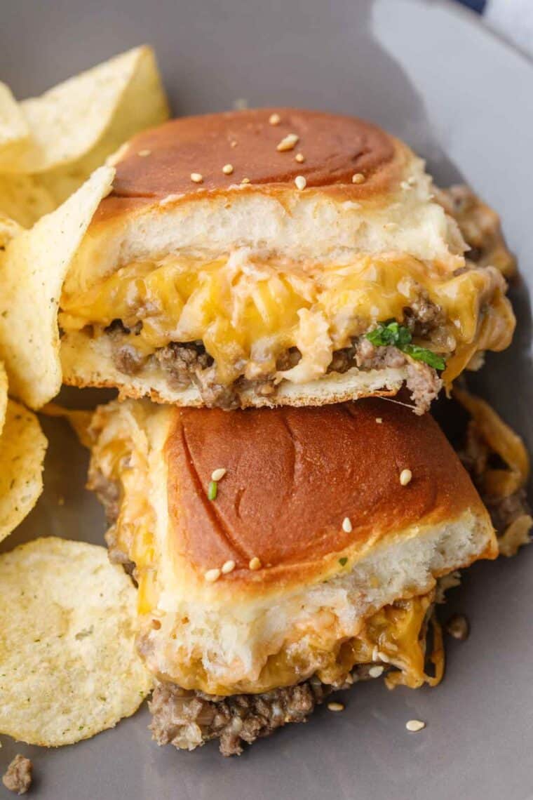 Up close of a cheeseburger slider on a dish with a side of chips.