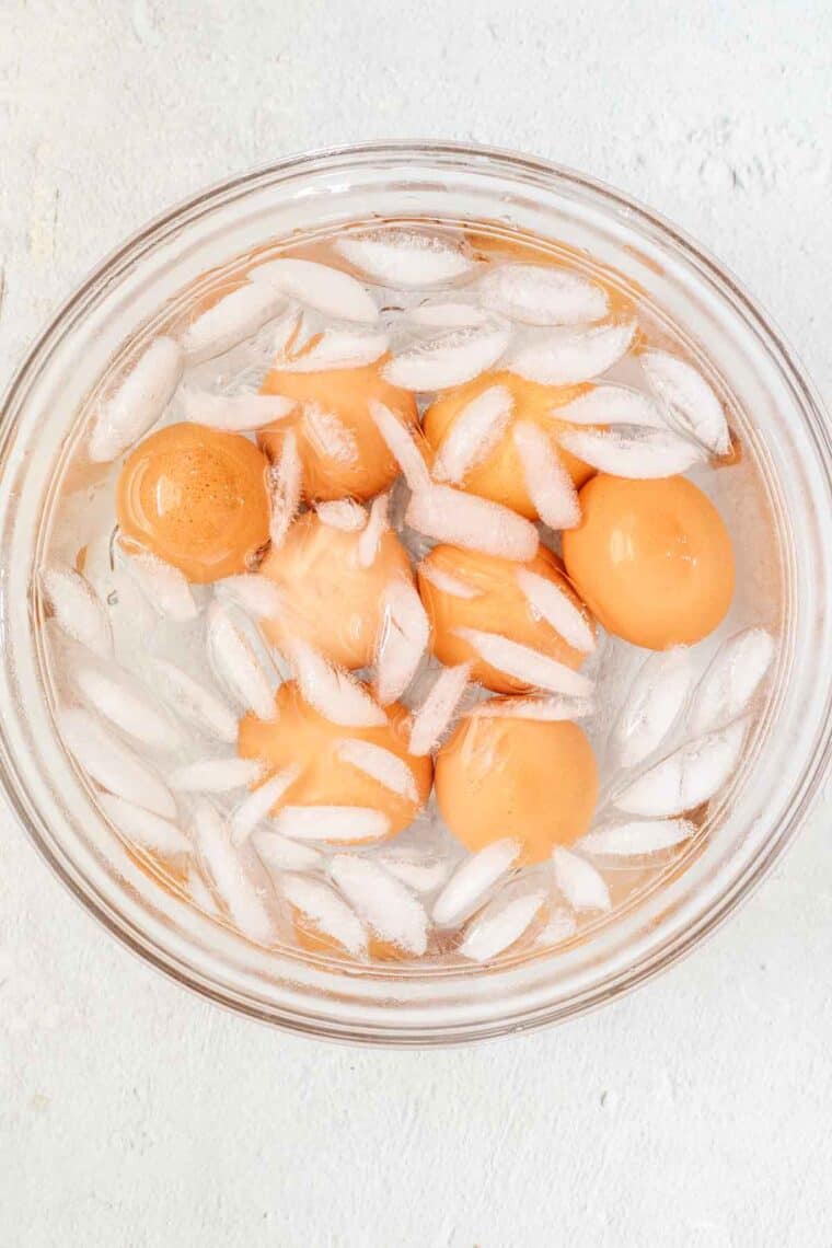 Hard-boiled eggs being cooled in bowl of ice and cold water.