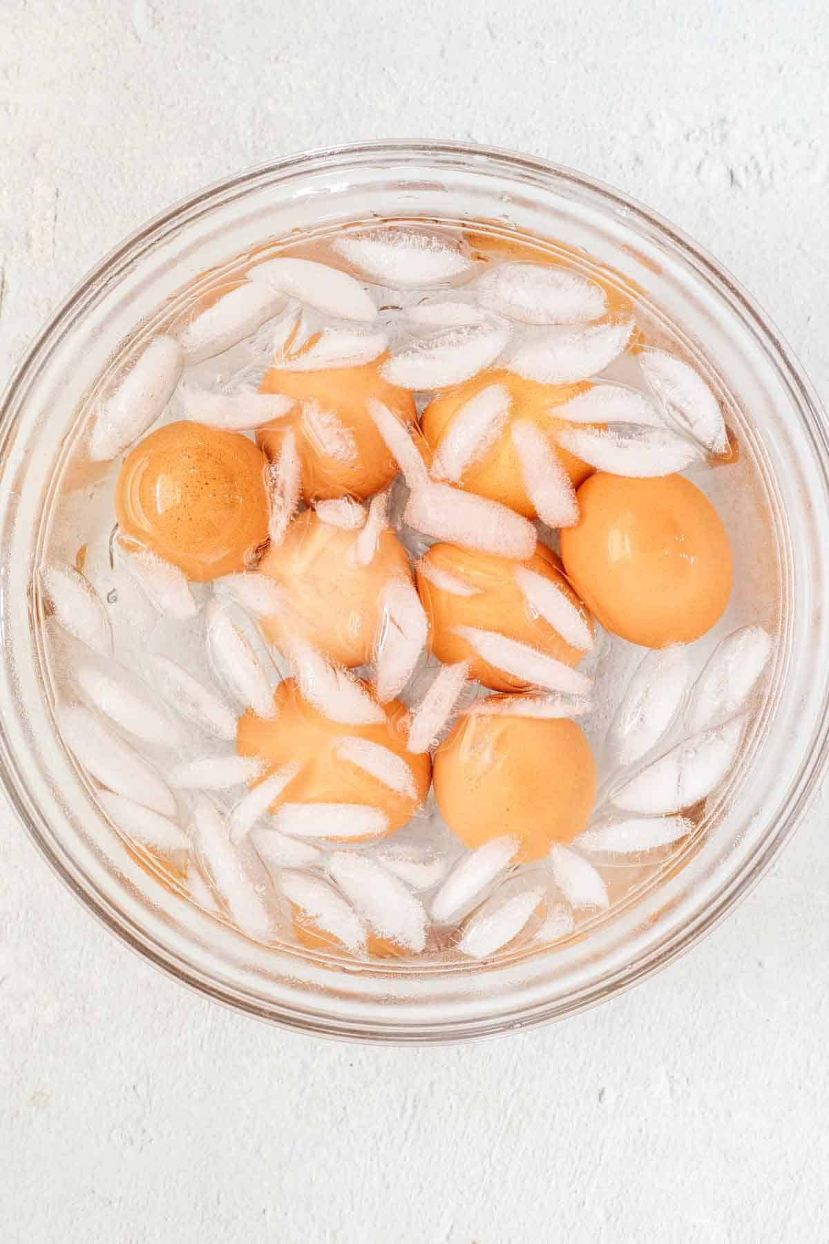 Boiled eggs being cooled in bowl of ice and cold water.