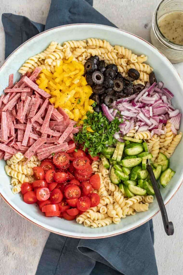 Pasta with salami, vegetable and homemade dressing in a large serving bowl.