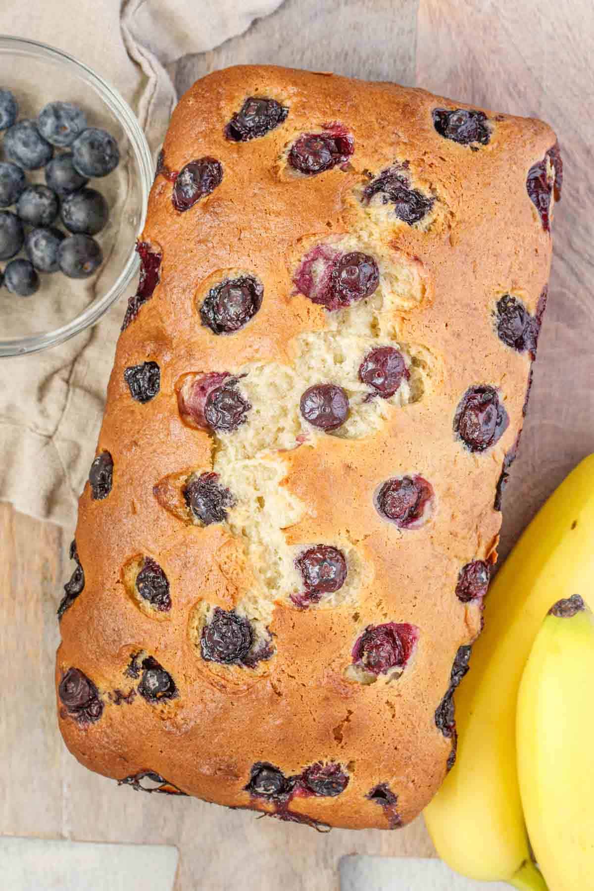Finished blueberry bread with blueberries and bananas on the side.