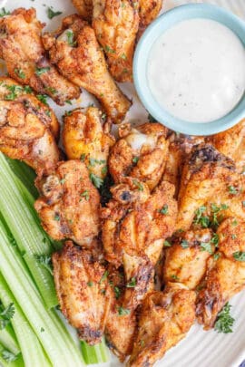 Close up image of wings on a serving plate with ranch and celery.