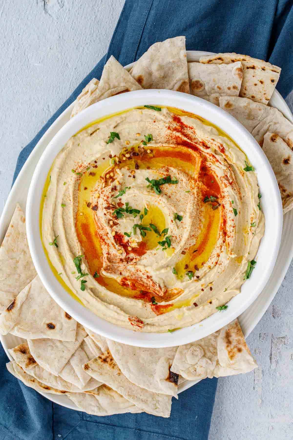 Hummus in a serving bowl with a side of pita bread.