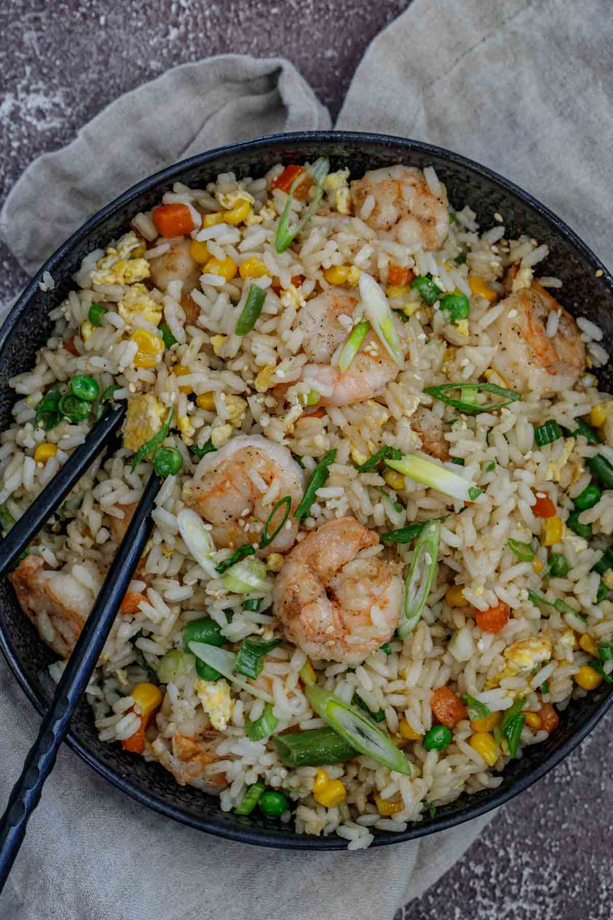 Close up of shrimp fried rice in a serving plate with chopsticks.
