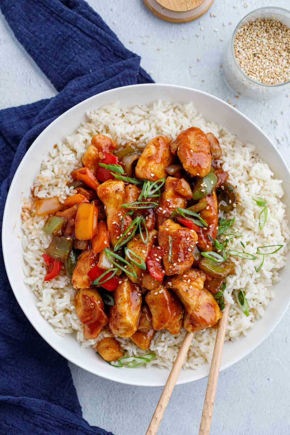 Sweet and sour chicken recipe topped on top of rice in serving plate.