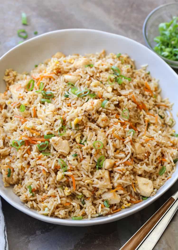 Chicken fried rice topped with greens and a fork on the side.