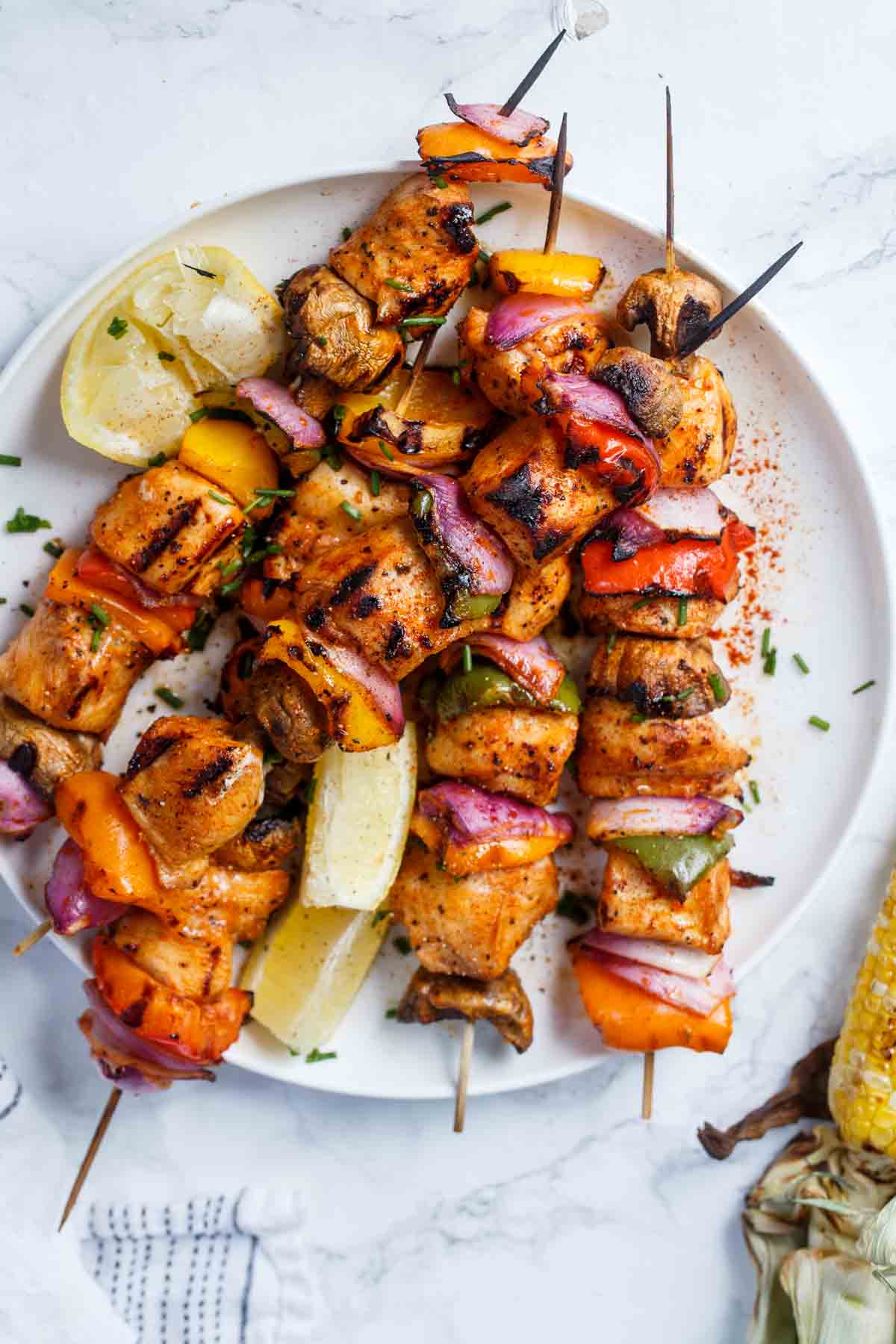 Kebabs on a stick with vegetables stacked on a plate.