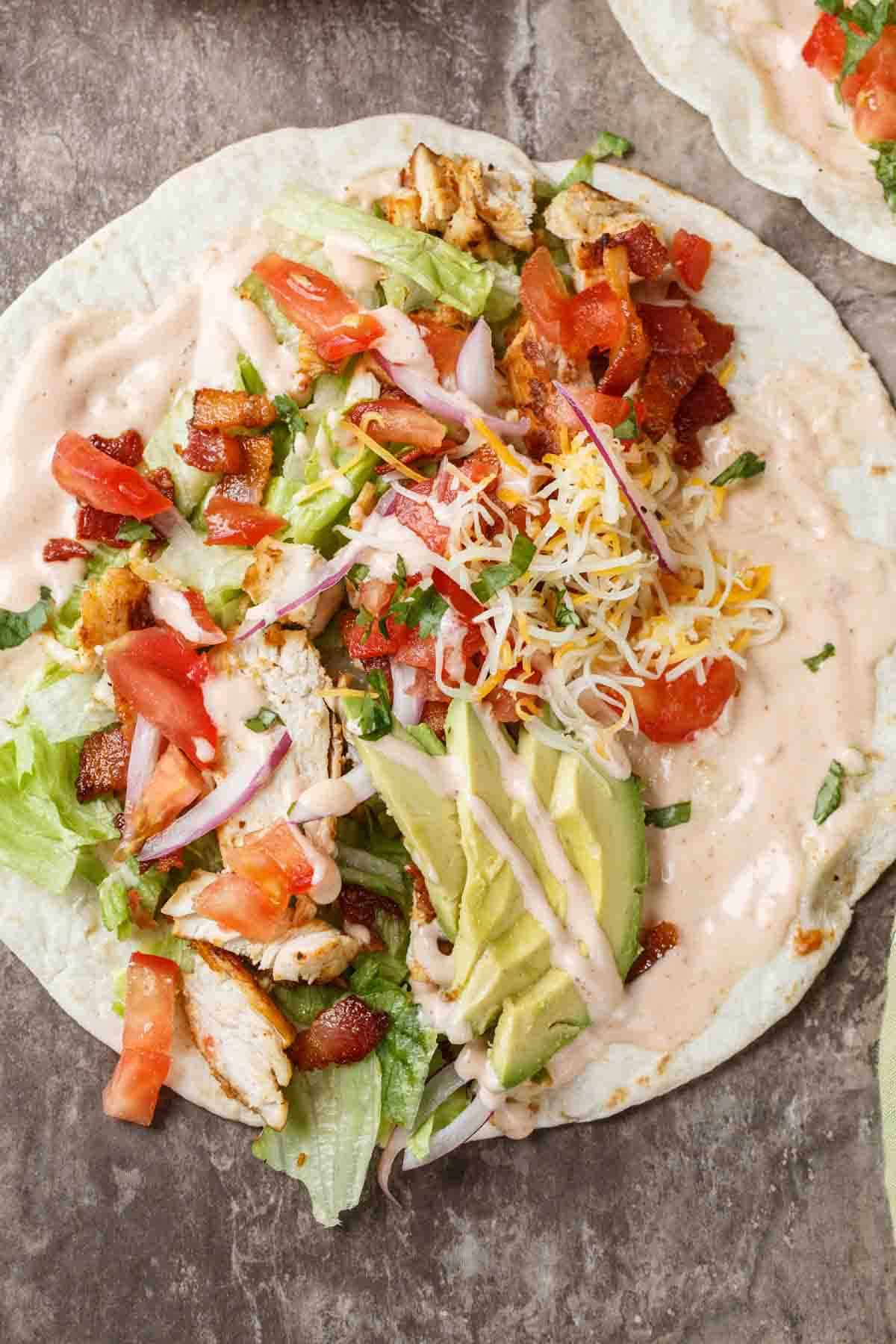 Upclose picture of a buffalo chicken wrapa, spicy buffalo ranch with chicken, cheese, lettuce and more toppings.