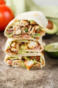 Stacked chicken wraps with avocado on the side.