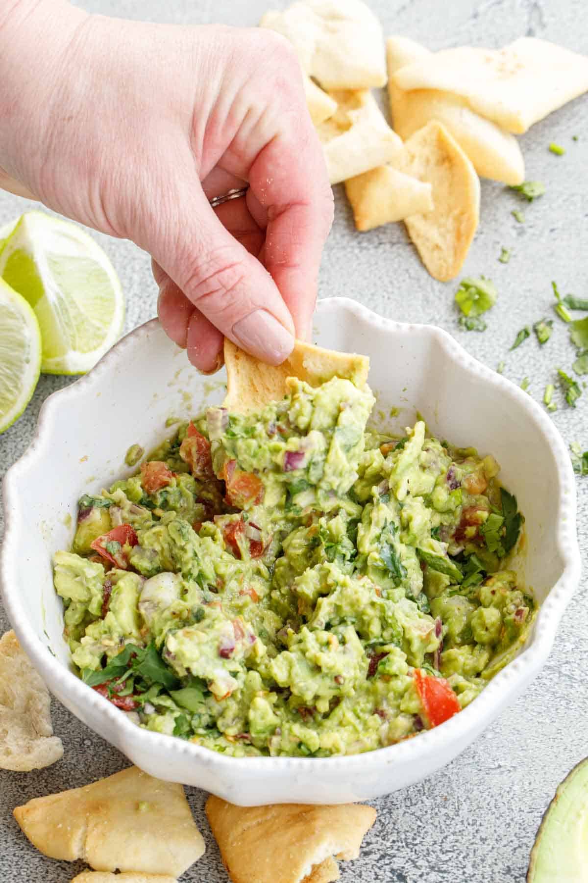 Easy guacamole recipe made in minutes! Guacamole in a bowl with fresh limes.