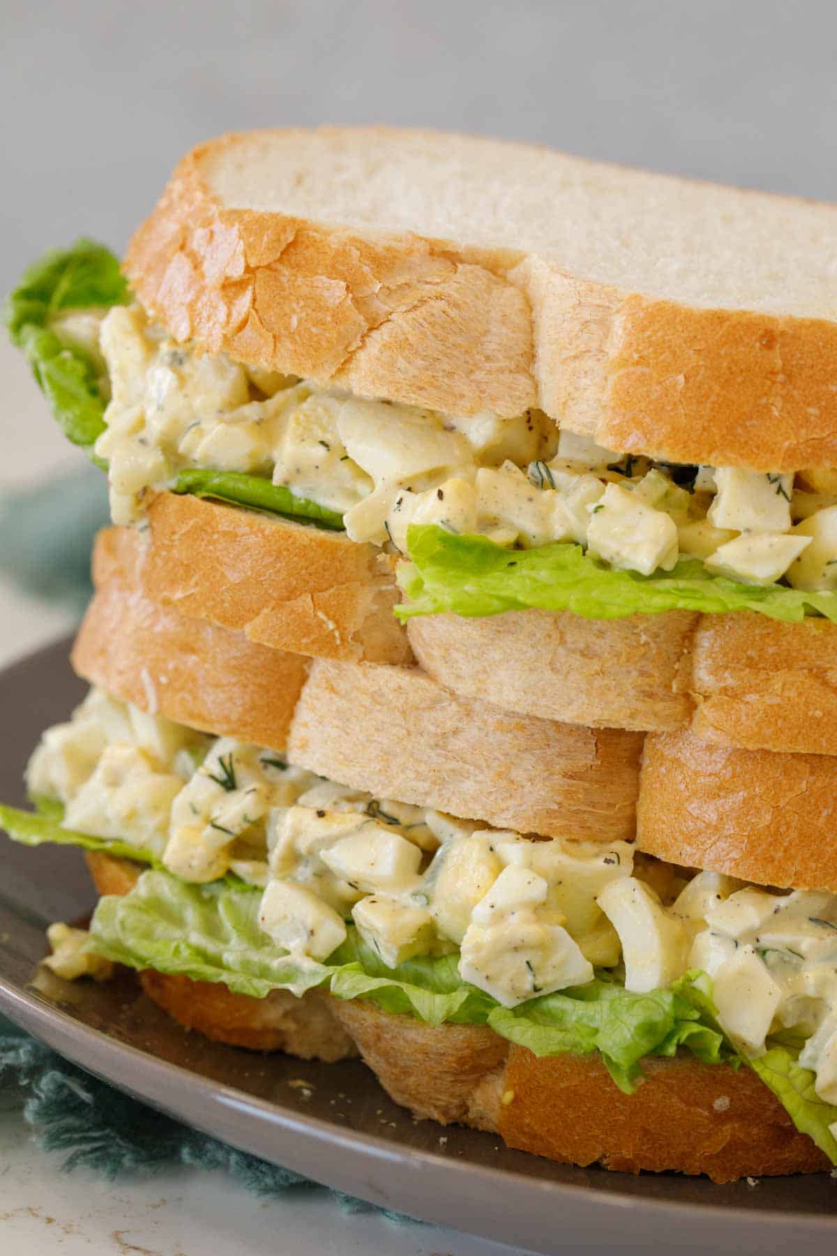 Egg sandwiches stacked on a serving plate.