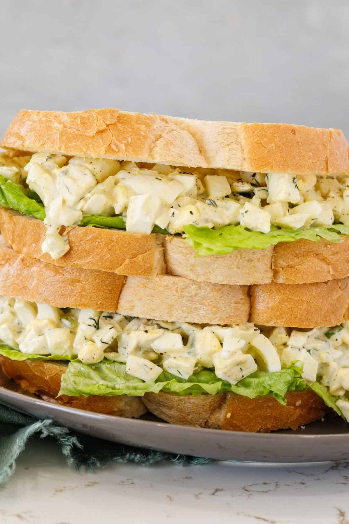 Two egg salad sandwiches stacked.