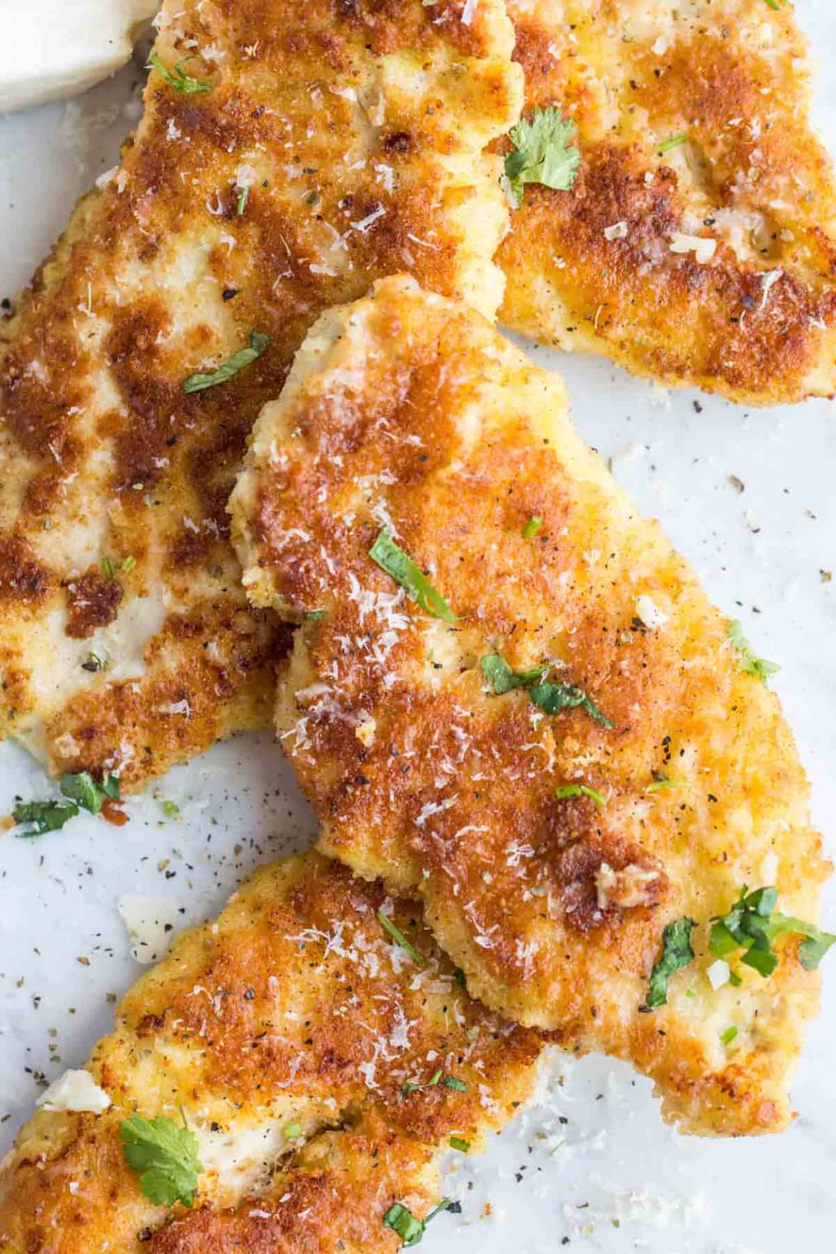 Close up image of crusted chicken topped with parmesan cheese.