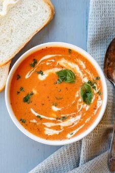 Tomato soup plated with a side of frsh bread.