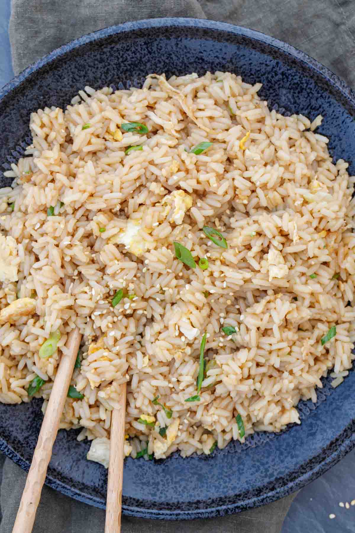Hibachi rice in a serving bowl with chop sitcks.