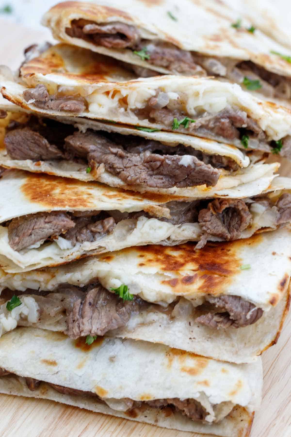 Quesadilla with steak cut into triangles stacked on a plate.