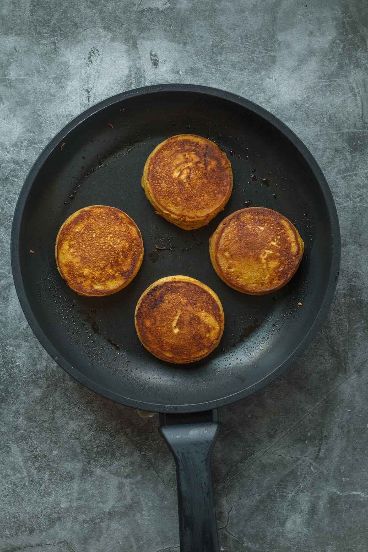 A skillet with pumpkin pancakes cooking on it.
