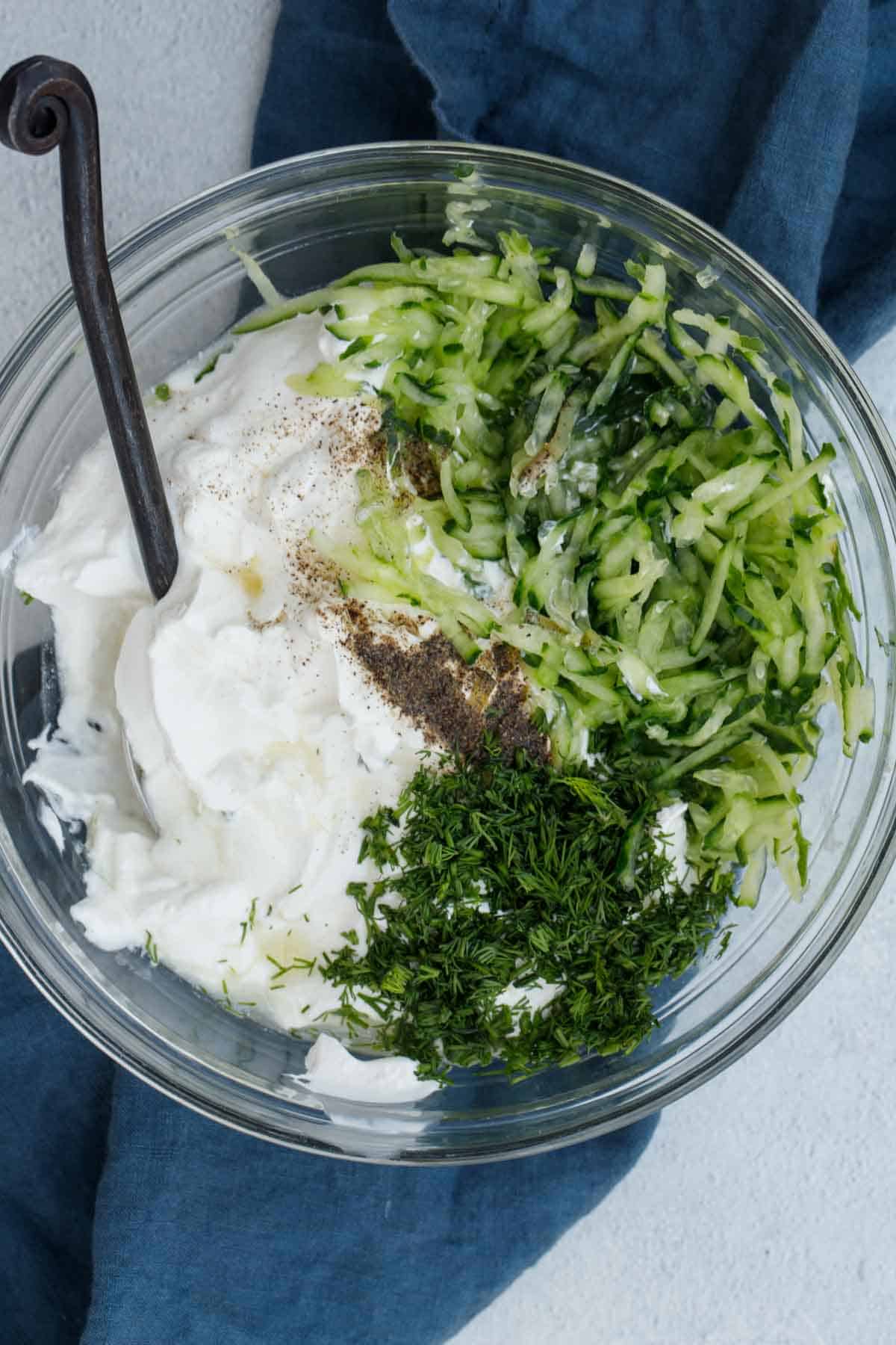 All ingredients for tzatziki sauce in a bowl unmixed.