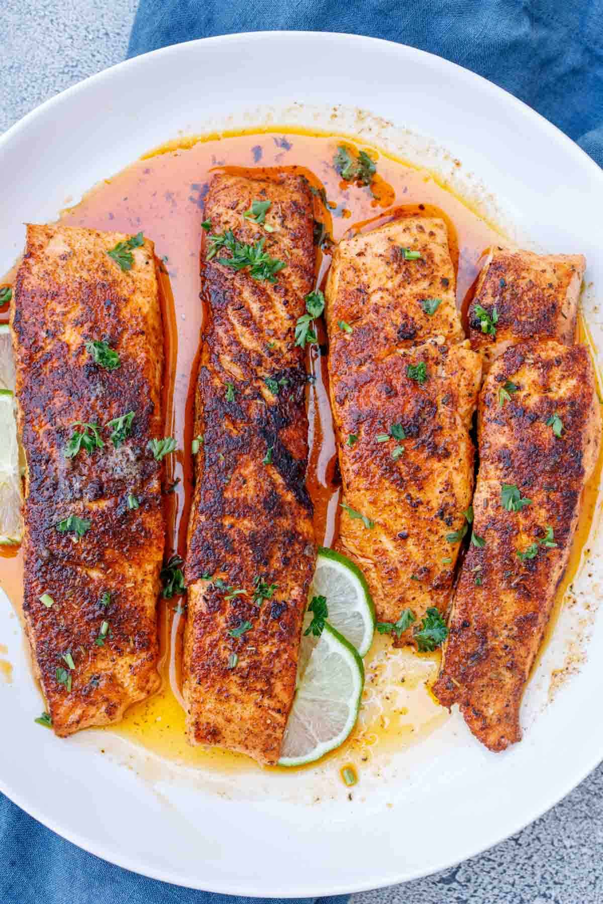 Blackened salmon fillets arranged next to each other on a plate.