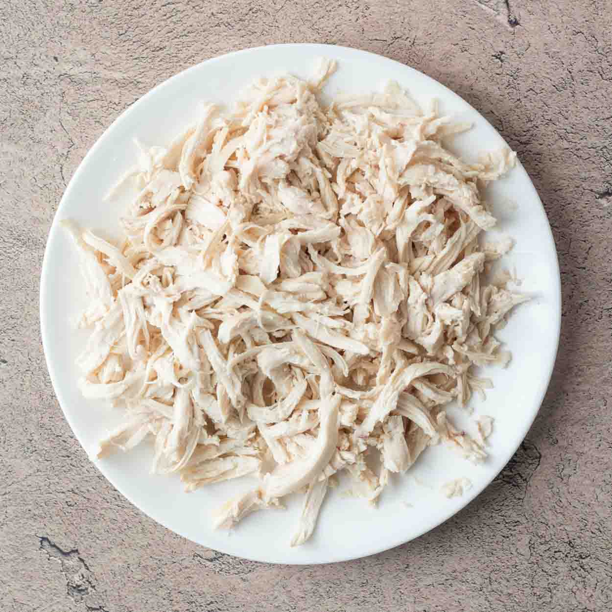 A plate containing cooked shredded chicken.
