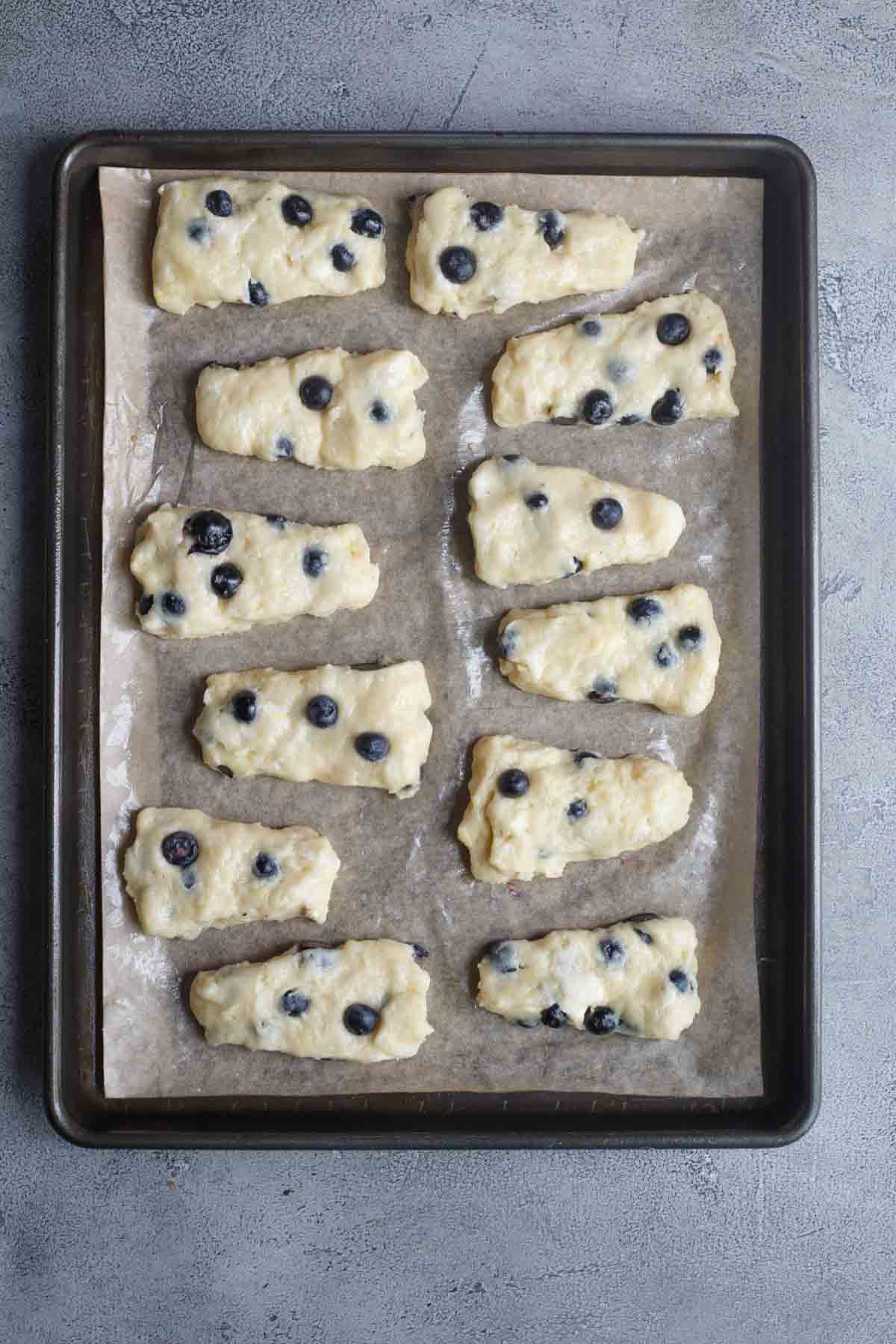 Divided blueberry scones, laid out on a baking sheet.