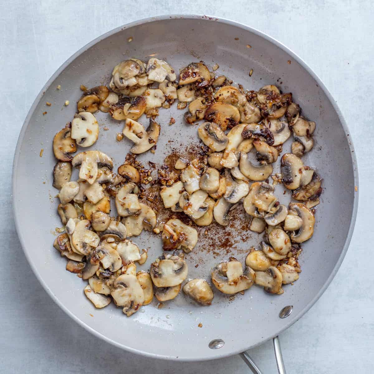 A skillet with added mushrooms. 