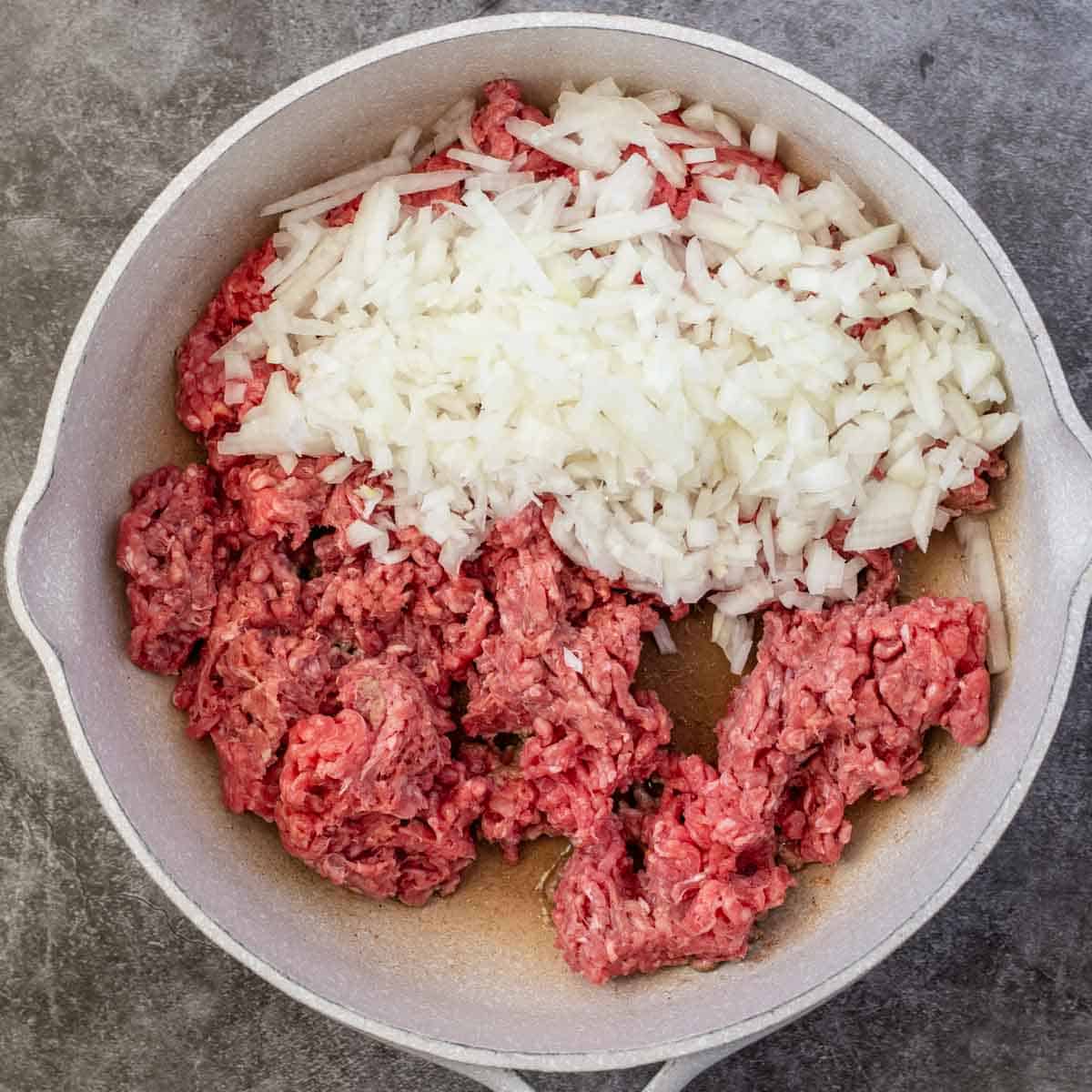 A skillet with ground beef and onion. 