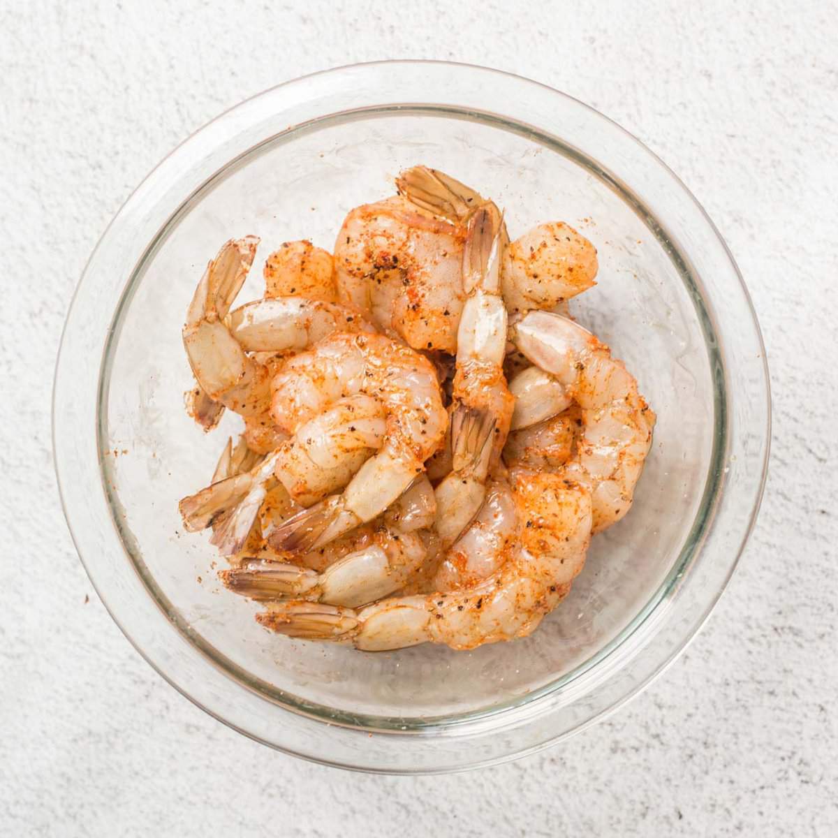 Seasoned shrimp in a glass bowl.