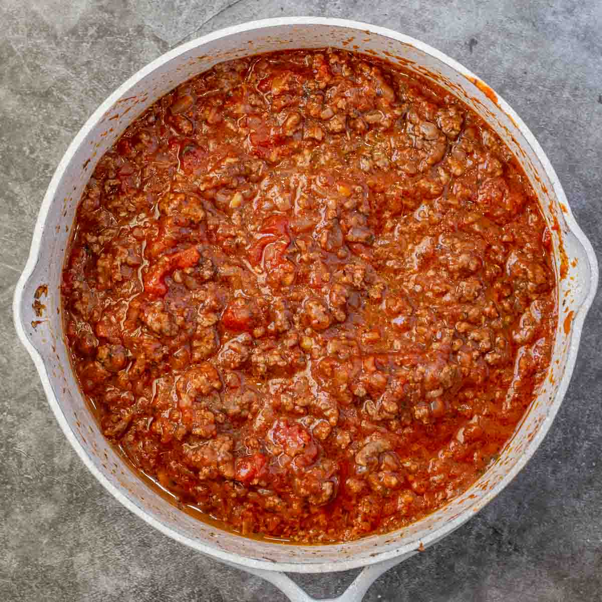 A skillet containing cooked ground beef with marinara sauce.