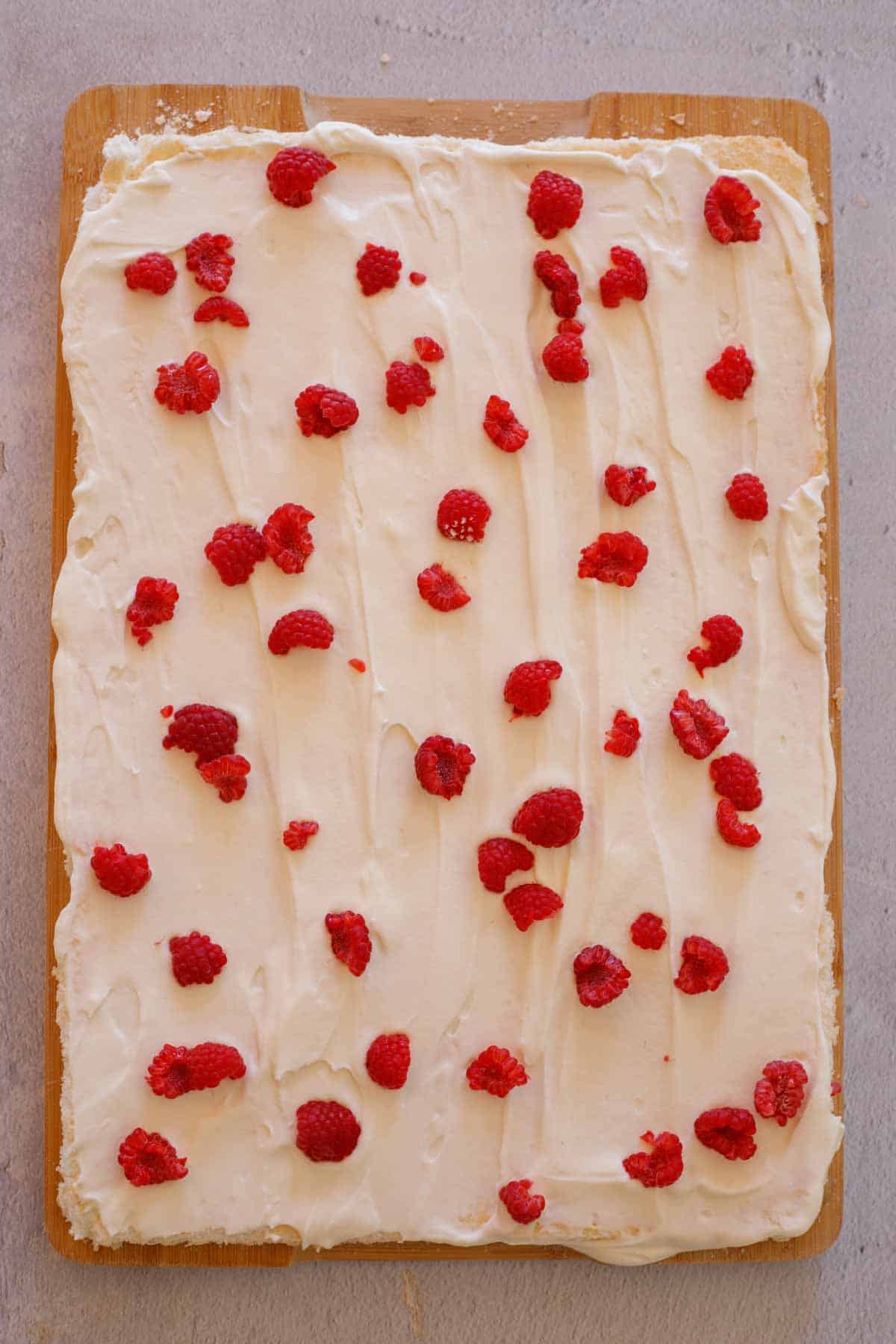 The cream evenly spread on the meringue along with raspberries. 