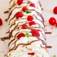 A berry meringue roulade, drizzled with chocolate, and topped with raspberries.