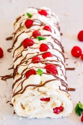 A berry meringue roulade, drizzled with chocolate, and topped with raspberries.