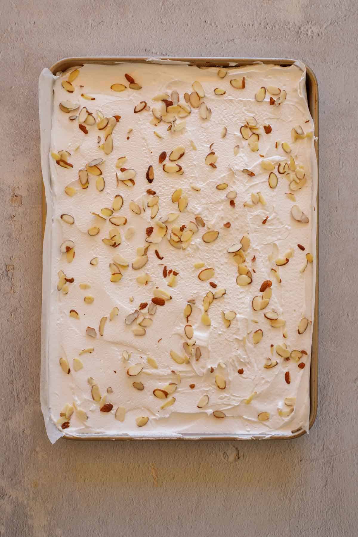 The meringue spread out on a baking sheet and topped with almonds. 