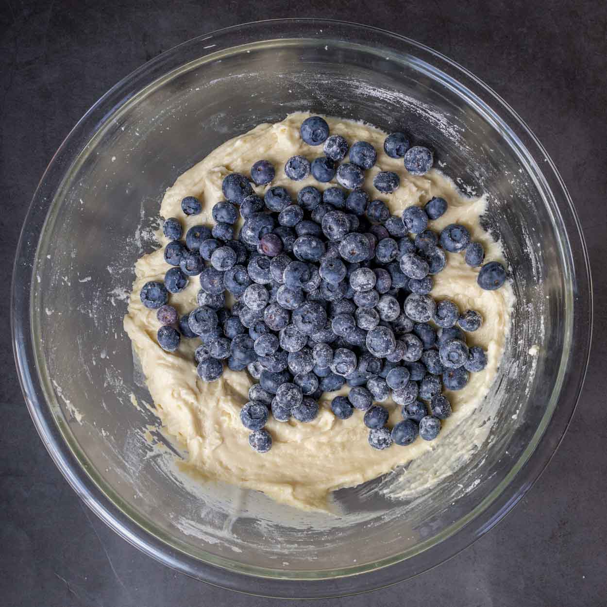 The glass bowl of batter with blueberries.