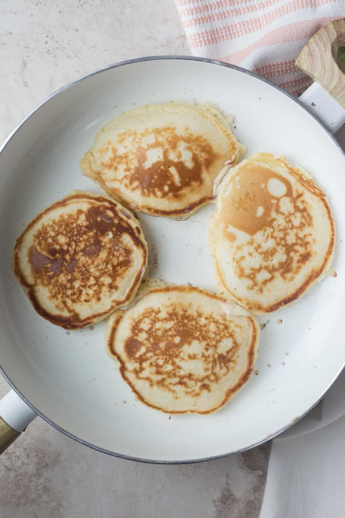 A pan with four cooking pancakes.