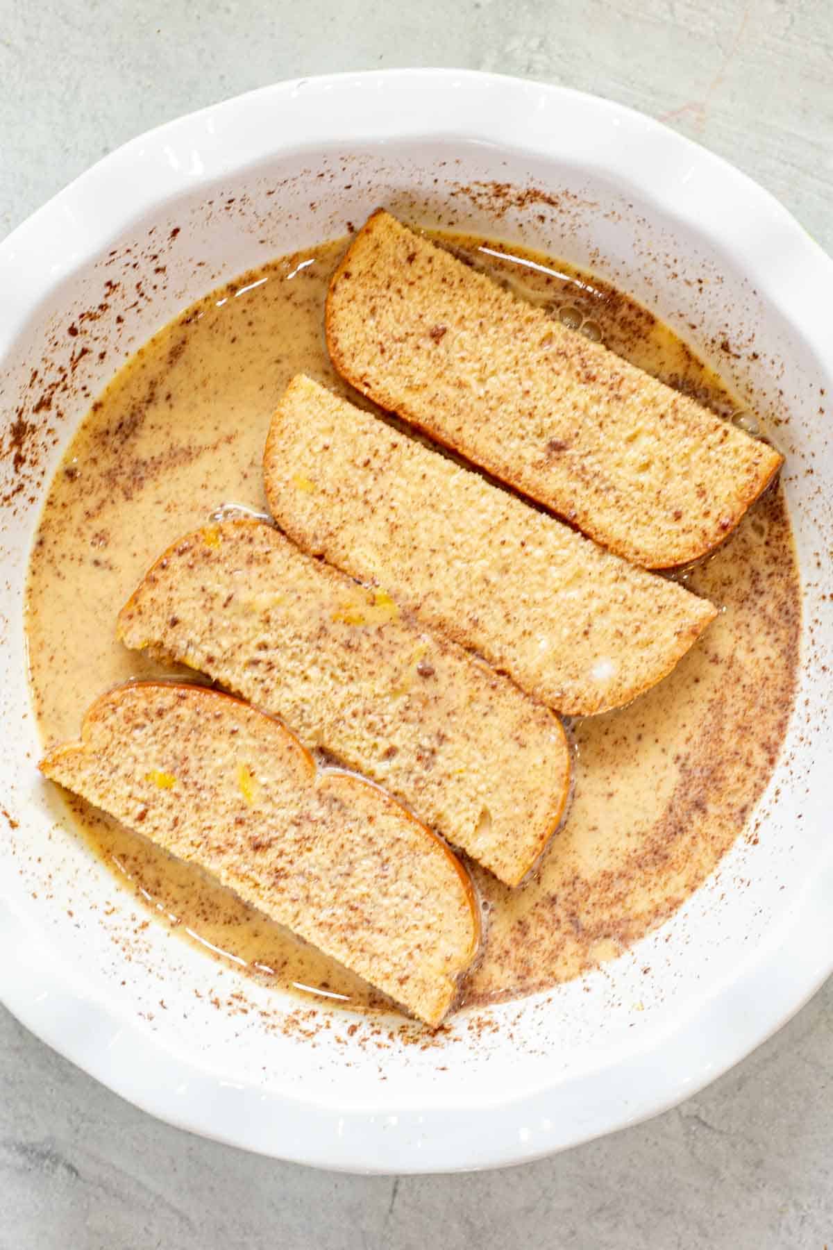 French toast sticks in a bowl of batter.