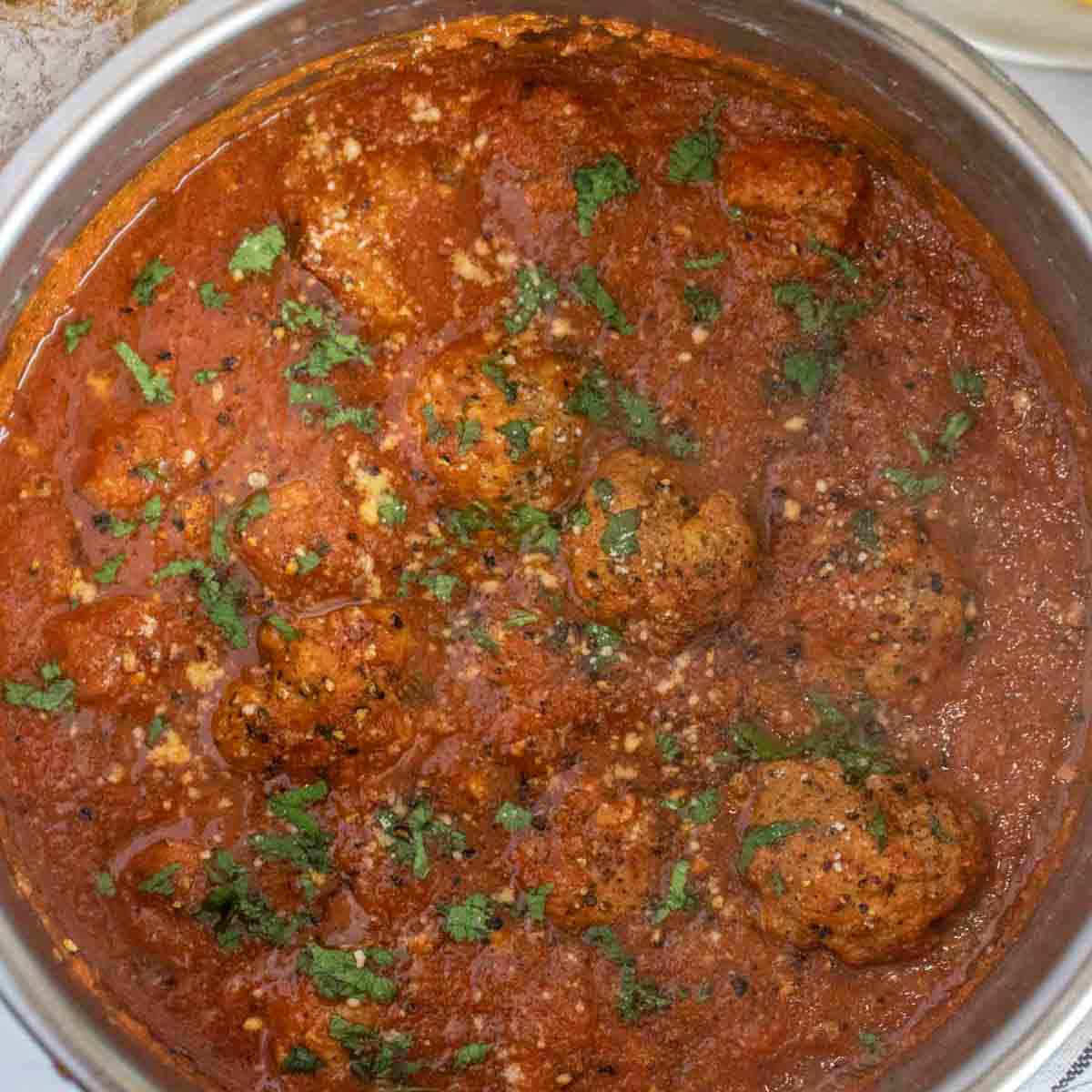 The cooked meatballs in the marinara sauce. 