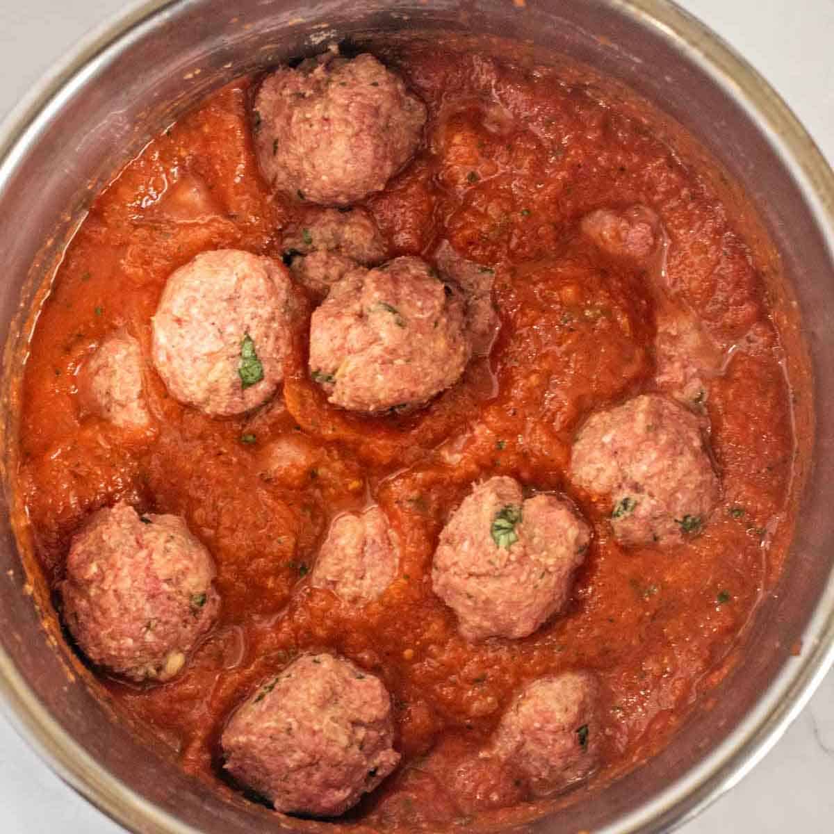 An instant pot with the cooking meatballs in the sauce.