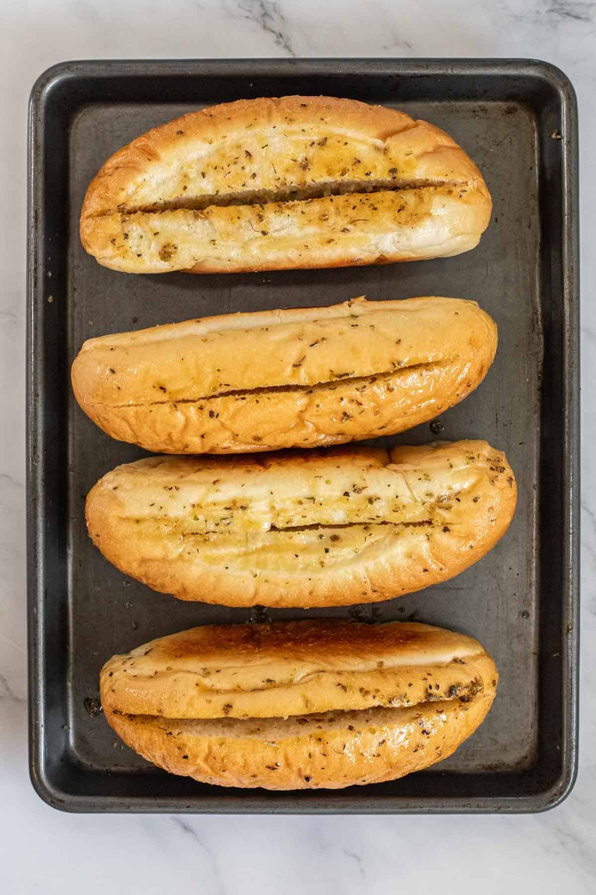 Hoagie buns on a baking sheet.