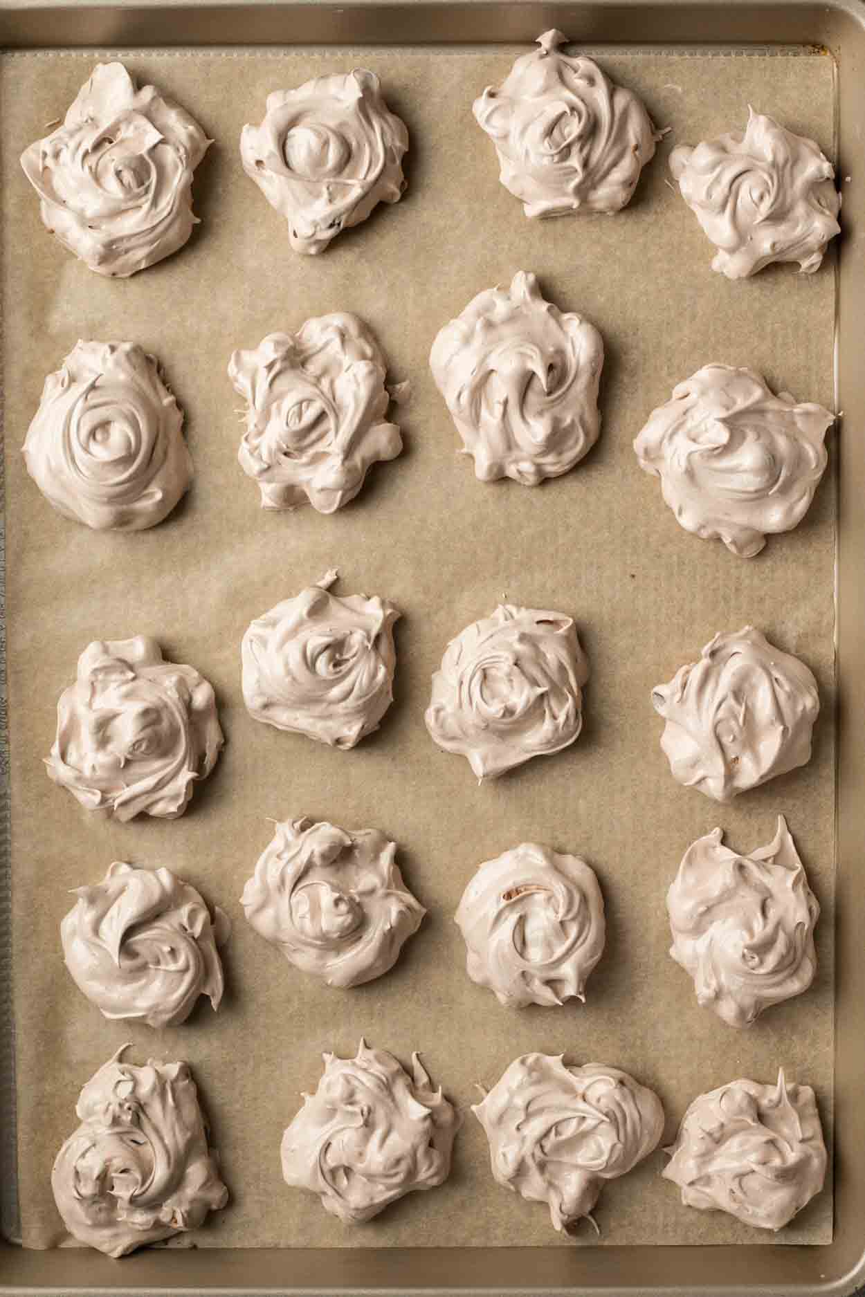 A baking sheet with the arranged meringue cookies. 
