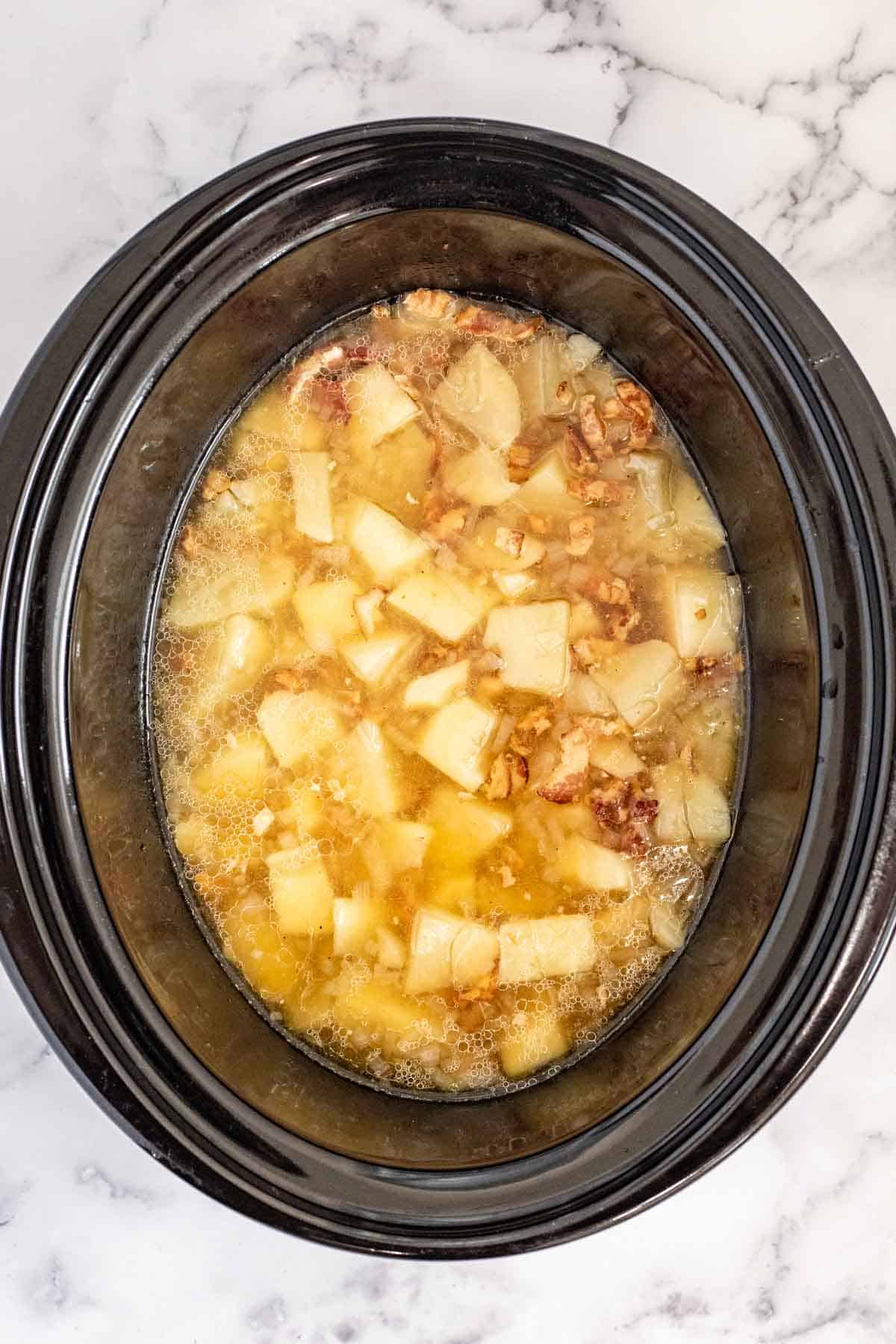 A crockpot with the cooking soup after the potatoes are fork tender.