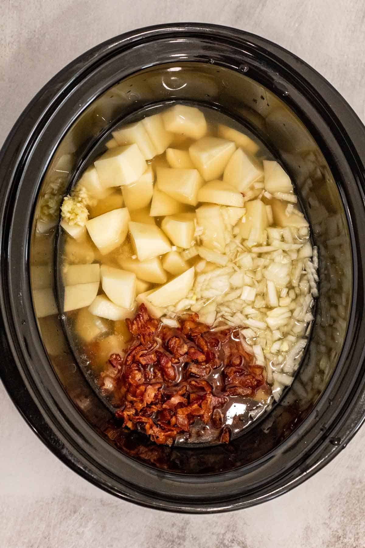 A crockpot containing all the ingredients for crockpot potato soup.